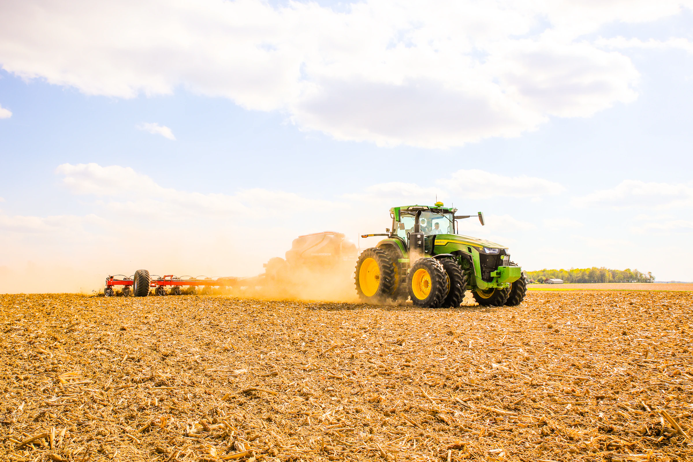 Tractor pulling agricultural equipment across a dry field